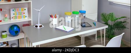 Salle de classe environnementale avec poubelles sélectives et moulin à vent au-dessus de la table Banque D'Images