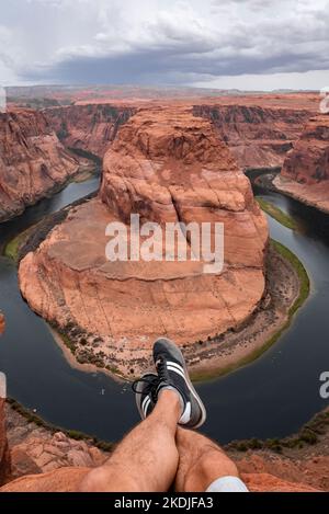 Partie basse de l'homme assis sur le Canyon au-dessus de Horseshoe Bend Banque D'Images