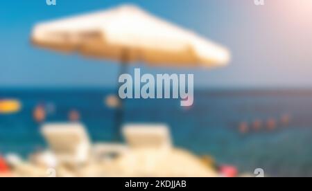 Abstrait flou défoqué fond été et mer fond. Les clients peuvent se détendre sur des chaises longues sous un parasol au bord de la mer. Vacances, vacances et Banque D'Images