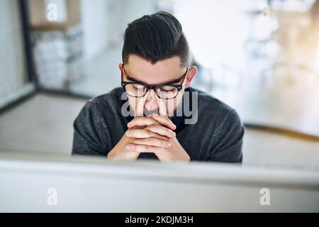 Regarder un écran d'ordinateur a tendu sa vue. Un jeune designer regardant stressé dehors tout en travaillant dans un bureau. Banque D'Images