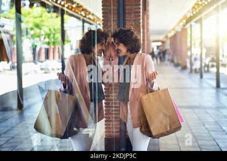 J'aime ce que je vois. Une femme qui se frapille à travers une fenêtre de magasins tout en étant sur une frénésie de shopping. Banque D'Images