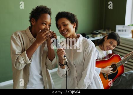 Jeunes écoliers jouant ensemble des chansons pendant la répétition avec accompagnement de guitare acoustique joué par une écolière asiatique Banque D'Images