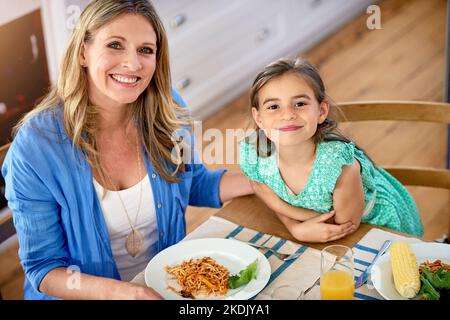 Mamans le numéro un cuisinier autour. Portrait d'une mère et de sa petite fille en train de savourer un repas ensemble à la maison. Banque D'Images