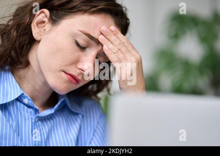 Une jeune femme d'affaires fatiguée se touchant la tête et ressentant de la fatigue migraine au travail. Banque D'Images