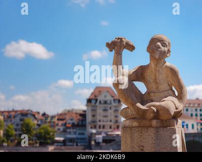 BÂLE, SUISSE, 7 JUILLET 2022: Fontaine Knabe mit Fisch ce qui signifie garçon avec le poisson près du Rhin et Mittlere Brucke pont du milieu dans la ville de Bâle. Banque D'Images