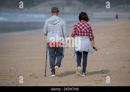 Un couple d'âge moyen marche main dans la main sur la plage d'A Lanzada, O Grove Banque D'Images