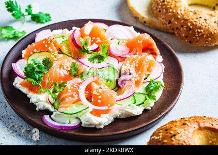 Plateau de beurre avec saumon salé, concombre, radis et coriandre sur une assiette en bois pour bagel. En-cas de fête, tendance à la cuisine. Banque D'Images