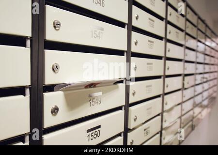 Boîtes aux lettres remplies de lettres et de factures dans un immeuble d'appartements. Une boîte postale débordante dans le couloir de la maison Banque D'Images