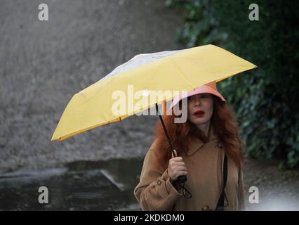 Une femme tenant un parapluie pendant une douche à effet pluie, sur Bankside à Londres. Date de la photo: Lundi 7 novembre 2022. Banque D'Images