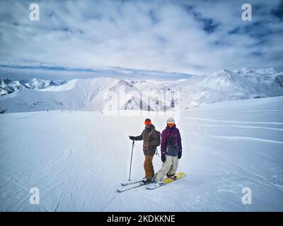 Skieur et snowboardeur debout sur le sommet de la montagne contre le ciel bleu et le panorama des montagnes. Deux amis actifs ont des vacances sur le concept de station de ski. Antenne Banque D'Images