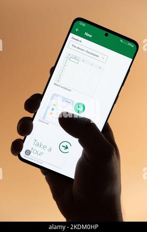 New york, Etats-Unis - 4 novembre 2022 : création d'un nouveau fichier Excel sur smartphone tenant à la main isolé sur fond marron Banque D'Images