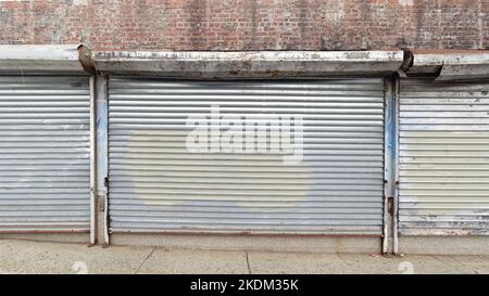 Volets roulants en acier ordinaire avec peinture sur un bâtiment fermé en brique dans le Bronx. Vierge pour l'utilisation de maquettes ou de publicités Banque D'Images