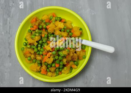 légumes mélangés pois, carottes, pomme de terre assiette enfant sur céramique Banque D'Images