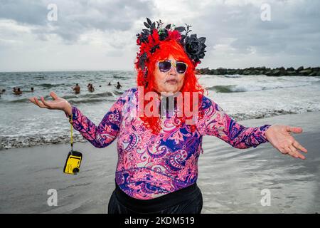 New York, New York, États-Unis. 6th novembre 2022. La saison hivernale commence pour le club de l'ours polaire de Coney Island avec une température de l'air de 66 et une température de l'eau de 60,6 à Bklyn. Les membres du club de natation d'hiver ont pris au dimanche de novembre exceptionnellement chaud. Faites du surf dans l'Atlantique, tandis que les spectateurs les ont applaudi depuis la plage et la promenade. Nageur coloré avec une perruque rouge sort du surf. (Image de crédit : © Milo Hess/ZUMA Press Wire) Banque D'Images