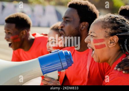 Les fans africains fous de football rouge célèbrent dans la foule tout en regardant le match au stade de sport - les supporters de football crient pour leur équipe pendant W Banque D'Images