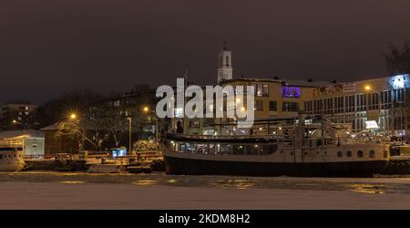 Turku, Finlande - 19 janvier 2016: Photo de Turku paysage urbain prise lors d'une nuit d'hiver sombre. Des maisons illuminées et des navires amarrés se trouvent le long de la côte de la rivière Banque D'Images