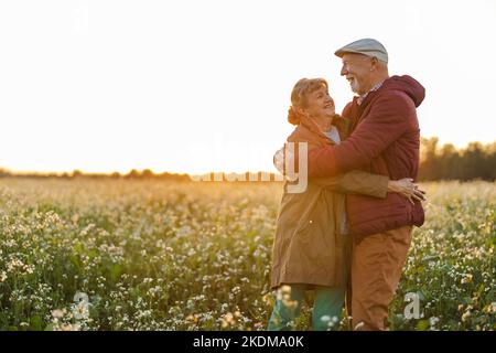 Couple senior dans un champ en automne au coucher du soleil Banque D'Images