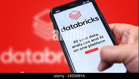 San Francisco, CA, US, mai 2022 : main tenant un téléphone avec la page Web de la compagnie Databricks à l'écran. Rouge arrière-plan flou. Databricks est une entreprise Banque D'Images