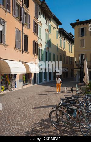 Femme marchant chien, vue arrière un matin d'été d'une jeune femme marchant ses deux chiens dans une rue pittoresque en Italie, Europe Banque D'Images