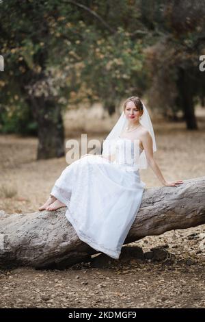 Mariée assise sur un grand arbre tombé dans le bosquet des chênes de Californie Banque D'Images