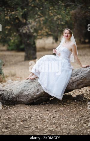 Mariée assise sur un grand arbre tombé dans le bosquet des chênes de Californie Banque D'Images