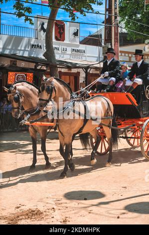 Chariot tiré par un groupe de chevaux avec des décorations et des personnes vêtues de vêtements traditionnels à la foire de Jerez Banque D'Images