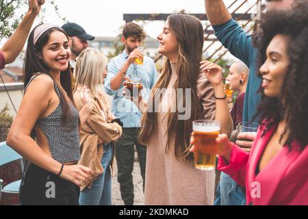 Communauté heureuse d'amis multiethniques qui s'amusent à danser ensemble à la fête sur le toit - les jeunes applaudissent à boire des bières sur la terrasse - internatio Banque D'Images