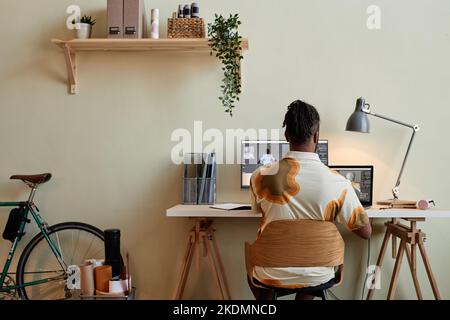 Vue arrière de l'homme noir créatif construisant des modèles numériques 3D à un minimum de bureau à la maison Banque D'Images