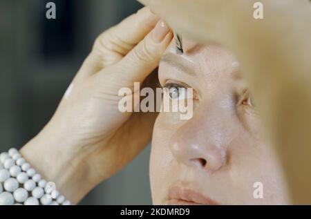 Colorier avec des lignes blanches le dessin de la forme des sourcils sur le visage d'une femme. Microblading. La beauté d'une femme. Banque D'Images