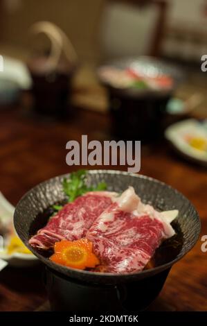 Un repas traditionnel japonais ryokan, composé de sukiyaki cuisiné en portions individuelles et de produits de saison, au Chojukan Ryokan, Hoshi Onsen, Gunma Banque D'Images