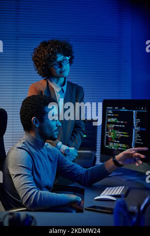 Ingénieur INFORMATIQUE ou développeur de logiciels confiant en pointant les codes sur l'écran de l'ordinateur tout en faisant une présentation à une collègue féminine Banque D'Images