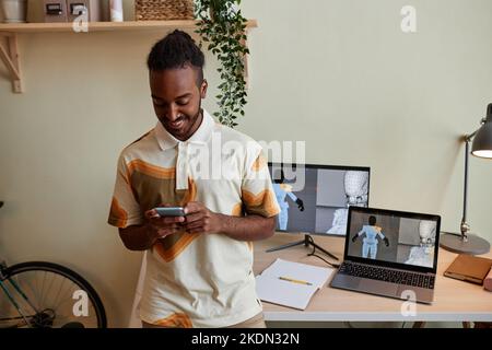 Portrait à la taille de l'homme noir créatif comme concepteur numérique 3D utilisant un smartphone par lieu de travail, espace de copie Banque D'Images
