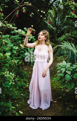 Femme portant un Rose Gown visitant un jardin idyllique Banque D'Images