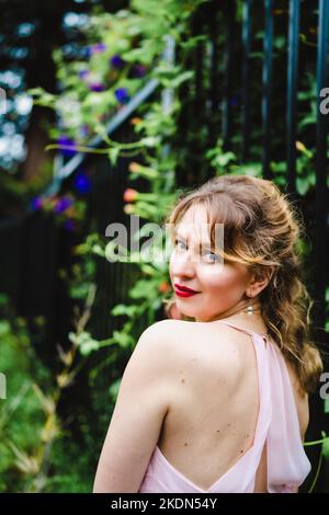 Femme portant un Rose Gown visitant un jardin idyllique Banque D'Images