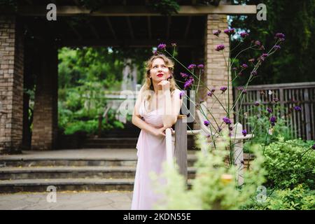 Femme portant un Rose Gown visitant un jardin idyllique Banque D'Images