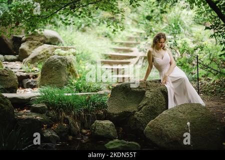 Femme portant un Rose Gown visitant un jardin idyllique Banque D'Images