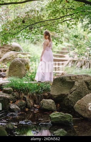 Femme portant un Rose Gown visitant un jardin idyllique Banque D'Images