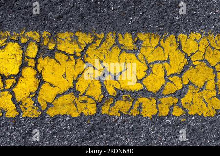 Ancienne ligne de marquage de route jaune endommagée comme arrière-plan Banque D'Images