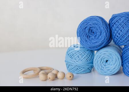 Gros plan de boules de macrame bleues sur une table blanche avec deux anneaux en bois et des perles en bois Banque D'Images