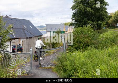 Route cyclable nationale 78 en Écosse modèle libéré femme d'âge moyen monte un e vélo le long du chemin, Écosse, Royaume-Uni Banque D'Images