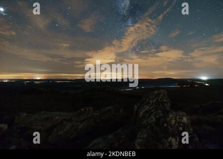 Paysage rocheux au sommet du Roc'h Trevezel la nuit avec des nuages qui couvrent légèrement la voie lactée, Parc naturel régional d'Armorique, Bretagne, France Banque D'Images