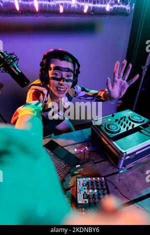 DJ producteur féminin mélangeant des sons sur des platines, en utilisant des boutons et des touches de basses pour mixer de la musique techno. Artiste musicien jouant avec un batteur à la discothèque, utilisant le panneau de commande électrique, disc jockey. Banque D'Images