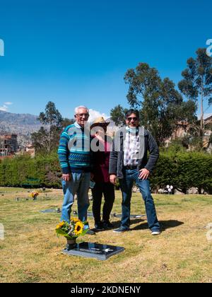 La Paz, Bolivie - 14 août 2022: Deux Boliviens avec une femme avec un chapeau au milieu regardent la caméra dans le jardin du cimetière sur un su Banque D'Images