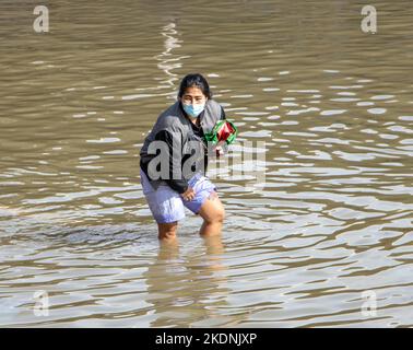 SAMUT PRAKAN, THAÏLANDE, OCT 29 2022, Une femme roule son pantalon en marchant dans une rue inondée Banque D'Images