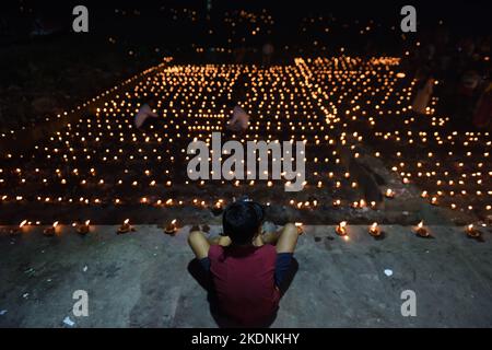 Kolkata, Inde. 7th novembre 2022. Un garçon est assis sur un ghat éclairé sur Ganga à l'occasion de Dev Deepavali, est le festival de Kartik Poornima, principalement célébré à Varanasi, Uttar Pradesh, Inde. Il tombe sur la pleine lune du mois hindou de Kartika et a lieu quinze jours après Diwali. Sur 7 novembre 2022 à Kolkata, Inde. (Image de crédit : © Sukhomoy  Sen/eyepix via ZUMA Press Wire) Banque D'Images