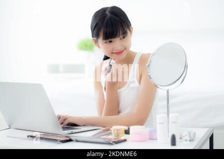 Beauté de la jeune femme asiatique avec apprendre le maquillage avec le rouge à lèvres sur la bouche regardant ordinateur portable avec tutoriel cours en ligne, l'enseignement féminin et expl Banque D'Images