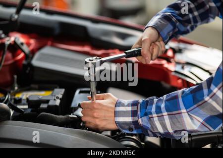 Mécanique automobile femelle en dévissant un écrou pour remplacer une bougie d'allumage de voiture. Banque D'Images