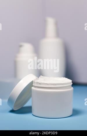 gros plan sur un pot blanc maquette avec de la crème sur fond bleu Banque D'Images