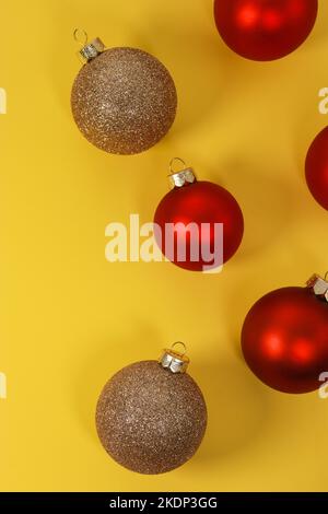 Boules décoratives de Noël rouges et dorées sur fond jaune. Flat lay, vue de dessus, espace de copie Banque D'Images