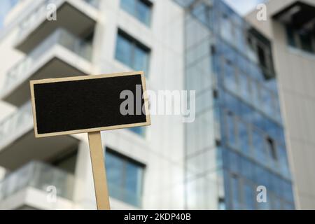 Blanc panneau noir contre le nouveau bâtiment d'appartement maquette vide maquette étiquette de tableau noir Maison à louer. Appartements à vendre. Panneau devant la nouvelle maison d'appartement. Espace de copie pour la publicité Banque D'Images